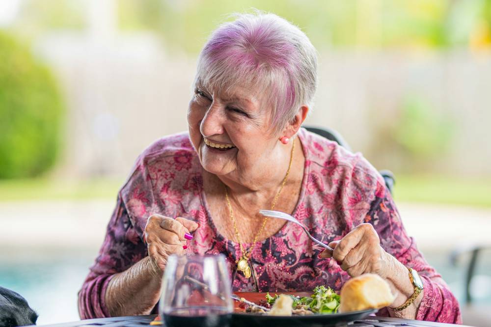 Uśmiechnięta seniorka przy obiedzie